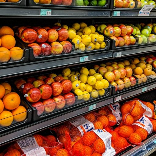 Shelves of fresh oranges, apples, lemons, and limes in a grocery store, illustrating cell phones as a commissary item