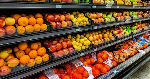 Shelves of fresh oranges, apples, lemons, and limes in a grocery store, illustrating cell phones as a commissary item