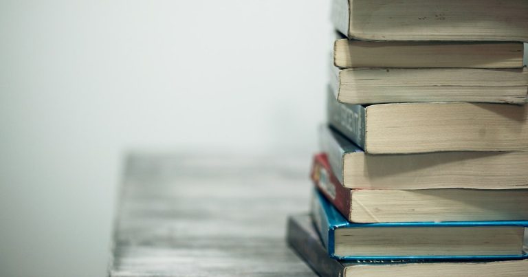 Assorted books on wooden table, illustrating a case for prison-friendly phones