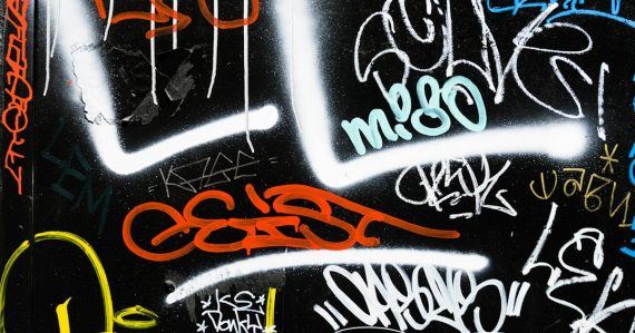 Black and multicolored graffiti art, illustrating gangs using phones behind bars