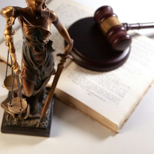 Statue of justice, gavel, and open book on table, illustrating a guard facing trial for smuggling