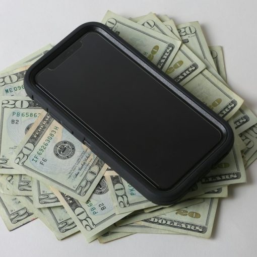 A cell phone sitting on top of a pile of money, illustrating prison phone price gouging
