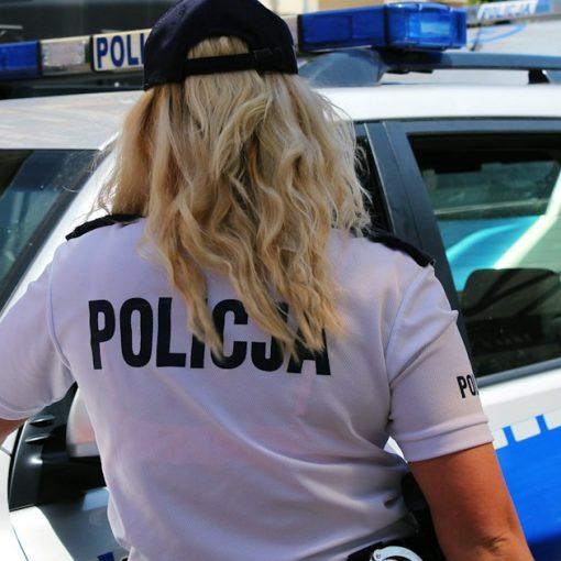 A police officer standing next to a police car, illustrating a prison raid finding 60 phones