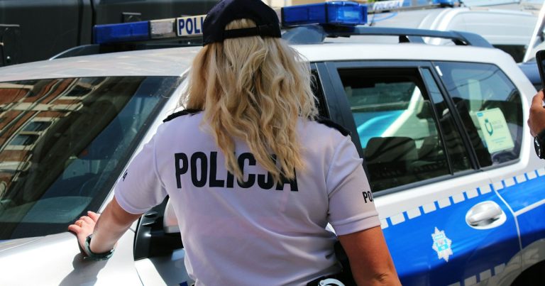 A police officer standing next to a police car, illustrating a prison raid finding 60 phones