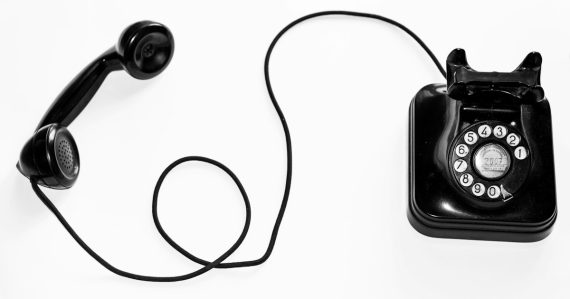 Photo of black rotary phone against white background, illustrating the dangers of prison wall phones