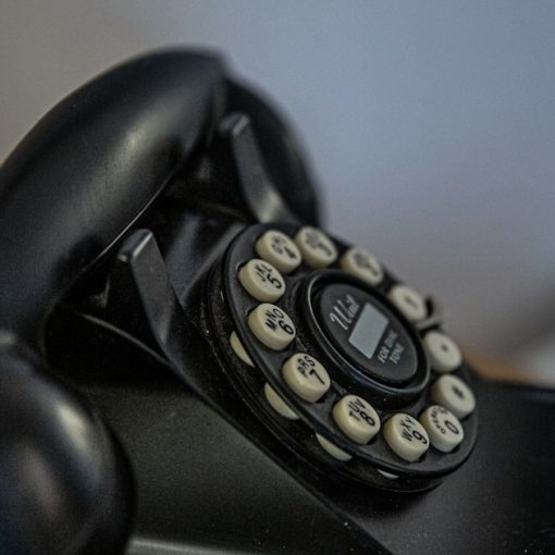 Black rotary telephone on black table, illustrating FCC cuts to prison call rates