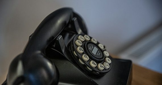 Black rotary telephone on black table, illustrating FCC cuts to prison call rates