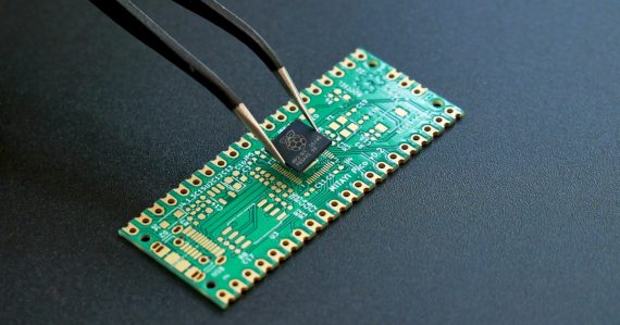 Tweezers placing a small microchip onto a circuit board, illustrating a dropped prisoner RFID trial