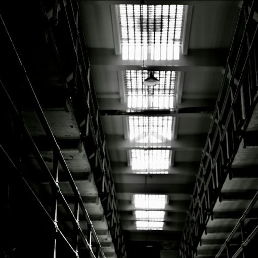 Dark, narrow hallway with bright, barred skylights, illustrating in-cell phones at HMP Birmingham
