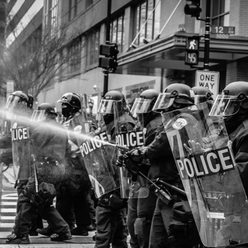 Grayscale photo of police riot team on pedestrian lane, illustrating a riot over confiscated phones