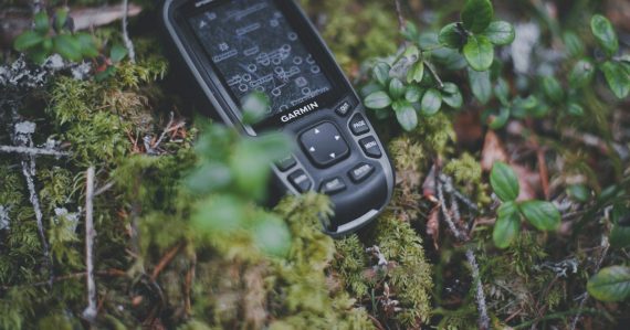 A cell phone sitting on top of a moss covered ground, illustrating satellite phones used by jailed terrorists