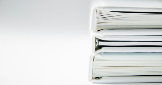 A stack of thick folders on a white surface, illustrating Securus suing Global Tel*Link