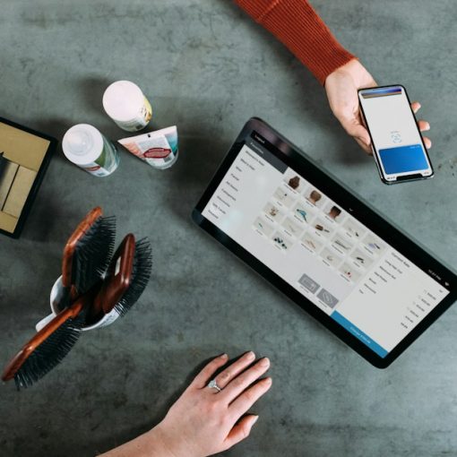 Person holding smartphone beside tablet computer, illustrating phones smuggled into prisons