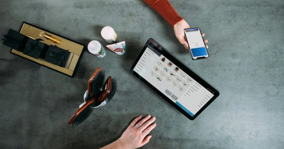 Person holding smartphone beside tablet computer, illustrating phones smuggled into prisons