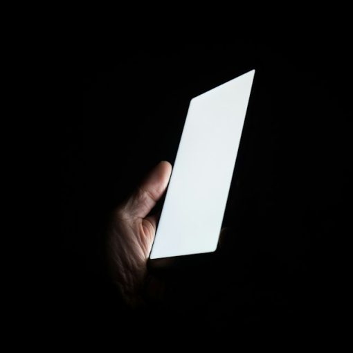 Person holding smartphone at night, illustrating contraband phones as a dangerous weapon