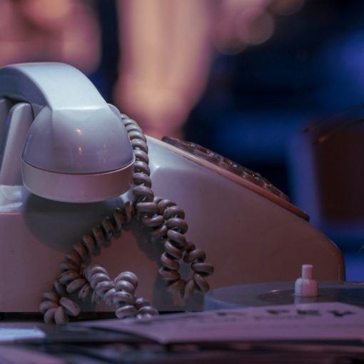 White and black corded telephone on white textile, illustrating landline phones installed in prison cells