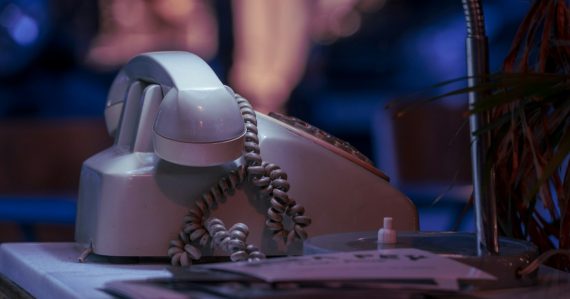 White and black corded telephone on white textile, illustrating landline phones installed in prison cells
