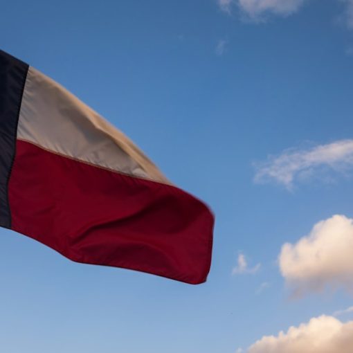 The Texas flag waves against a blue sky, illustrating Texas investing in phone blocking