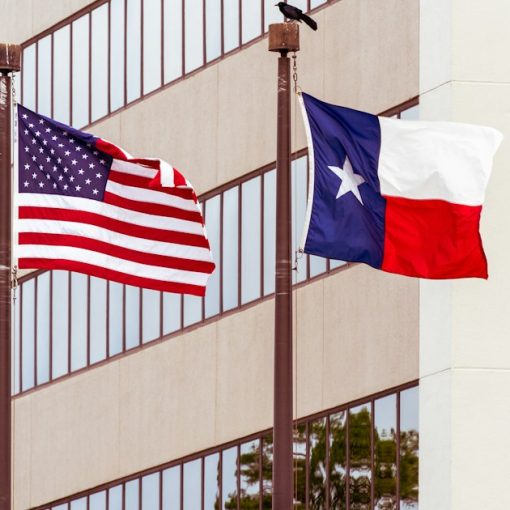 Texas Flag and USA flag on poles, illustrating a video on phones in Texas prisons