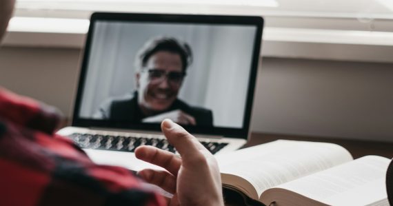 Person in a plaid shirt using a laptop computer, illustrating video visits replacing jail visits