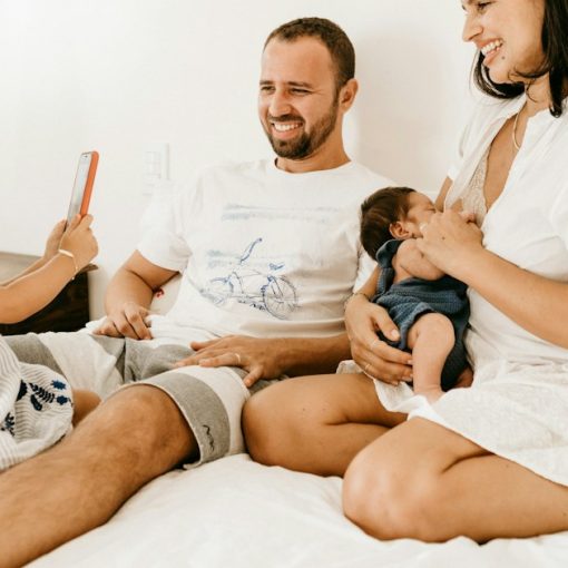 A family on a bed, a child holding a phone, an adult holding a baby, illustrating the challenges of jail visits