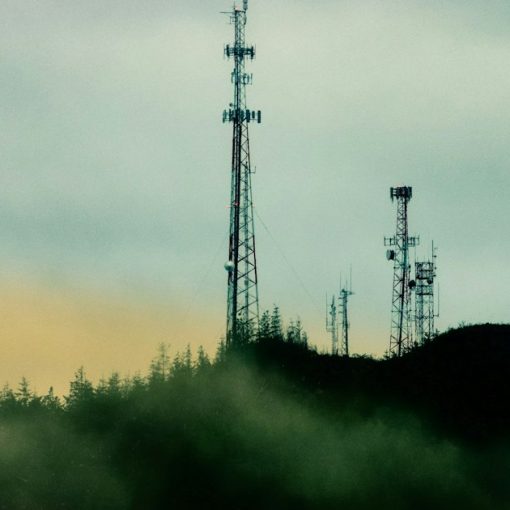 A cell tower on top of a hill next to a forest, illustrating carriers opposing prison jamming