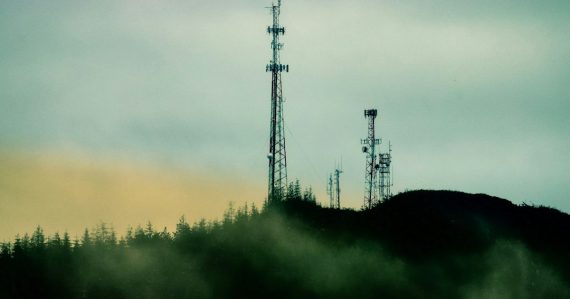 A cell tower on top of a hill next to a forest, illustrating carriers opposing prison jamming