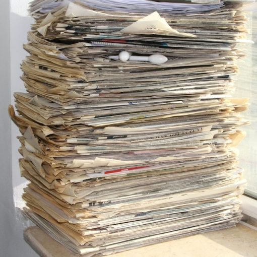 A stack of newspapers sitting on a window sill, illustrating contraband phone news briefs