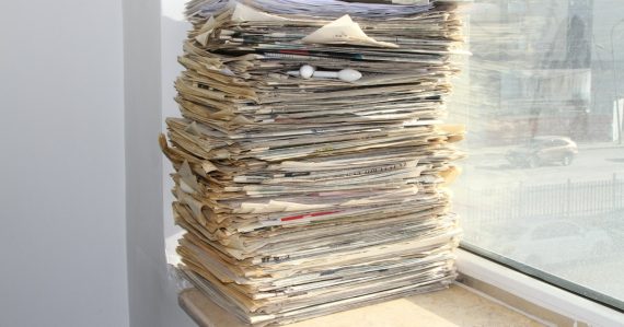 A stack of newspapers sitting on a window sill, illustrating contraband phone news briefs
