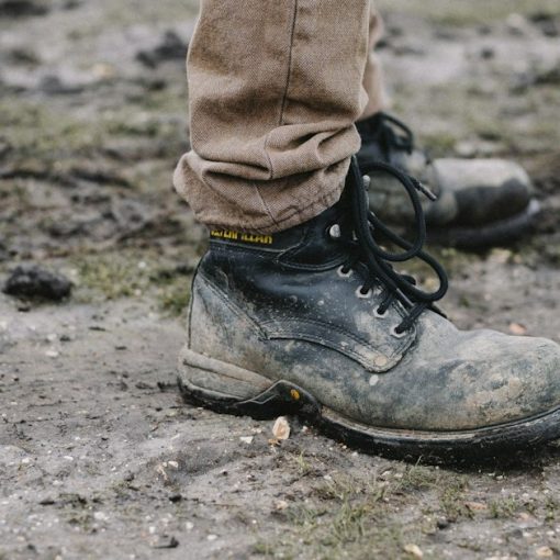 Person in black work shoes standing on dirt pathway, illustrating work release phone smuggling