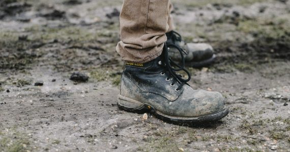 Person in black work shoes standing on dirt pathway, illustrating work release phone smuggling
