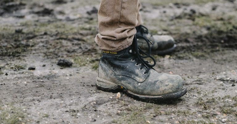 Person in black work shoes standing on dirt pathway, illustrating work release phone smuggling